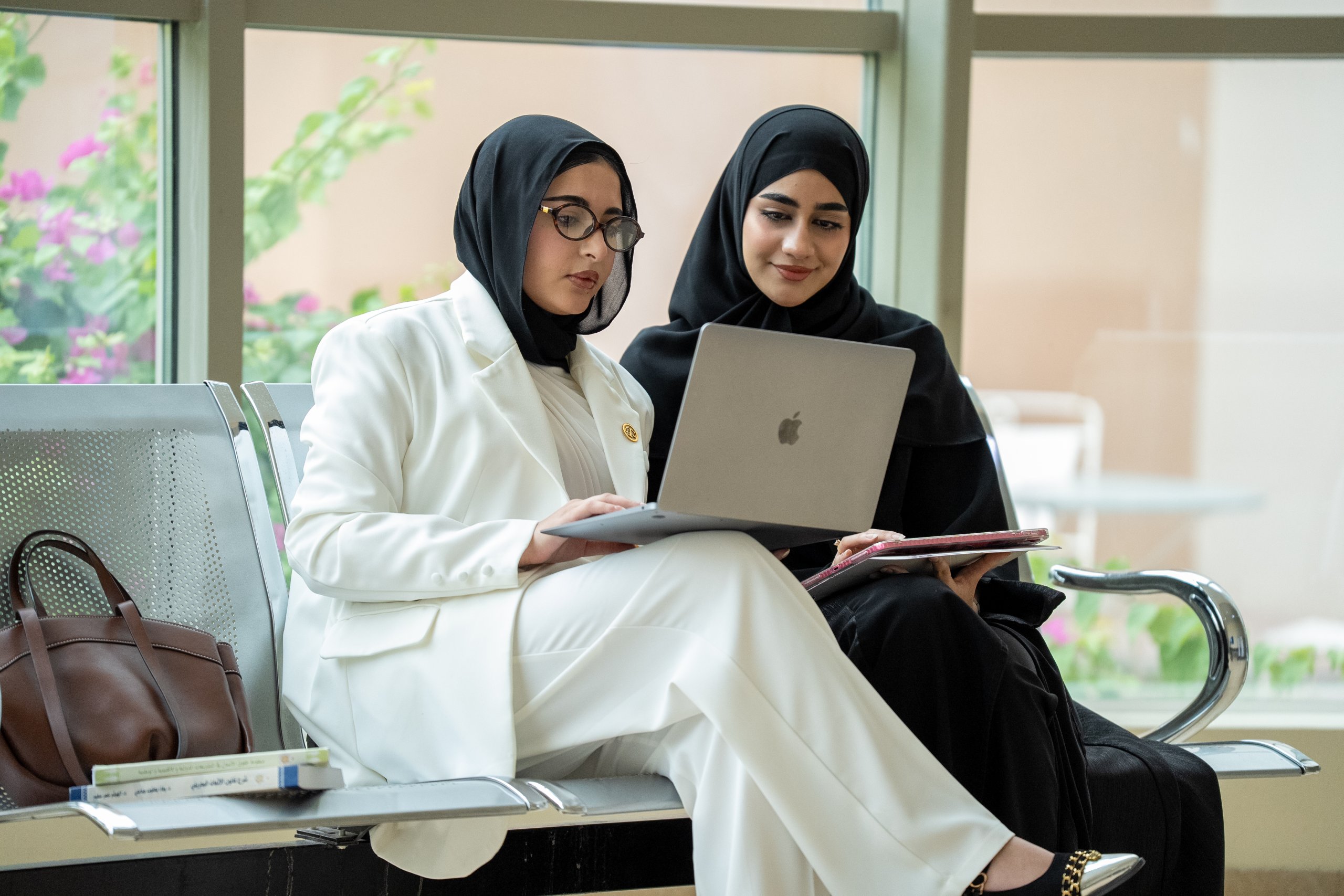 Two female students collaborating on a laptop on campus